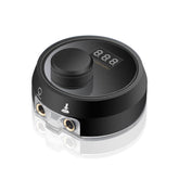 Tattoo Machine Power Supply. Black round unit with a central knob and digital display on top, and clear input ports on the side.